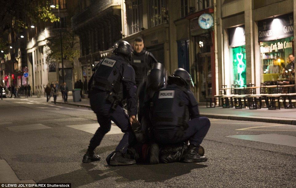 French riot police appear to hold a man down on the streets of Paris, following a series of deadly attacks in the French capital.