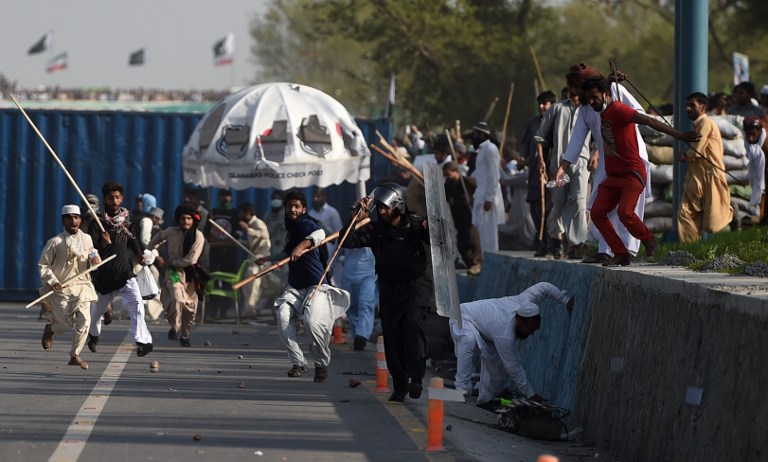 Pakistani Frontier Constabulary officials run from supporters of executed Islamist Mumtaz Qadri during an anti-government rally in Islamabad on March 27, 2016. Pakistani police fired tear gas at thousands of stone-throwing supporters of an Islamist assassin, a month after he was hanged for killing a provincial governor for alleged blasphemy. / AFP / FAROOQ NAEEM
